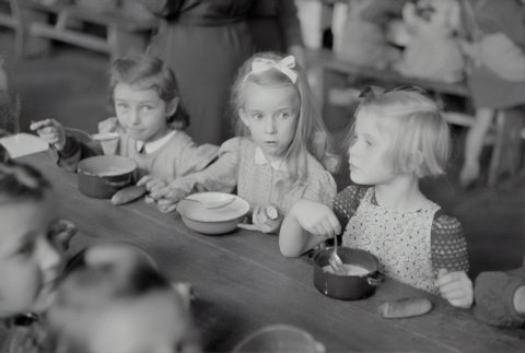 Børn spiser suppe ved et bord.
