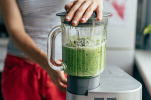 Person laver grøn smoothie i blender