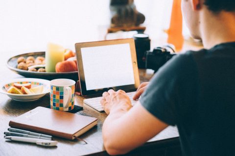 Person arbejder på en tablet ved et bord.