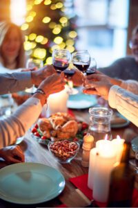 Skål ved julebord med lys, mad og vin.