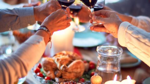 Skål ved julebord med lys, mad og vin.