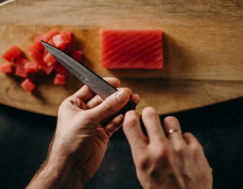 Person skærer tunfisk på skærebræt