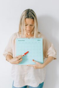 Kvinde noterer i kalender ved skrivebord