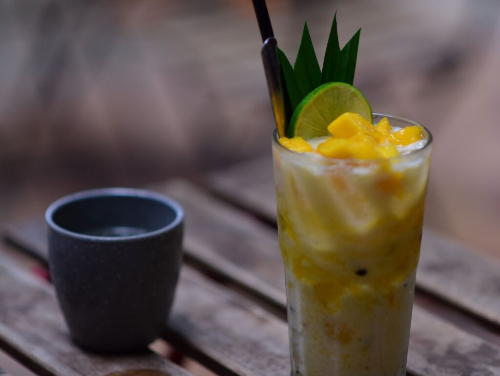 Højt glas med mango-lemonade, mangotern og kugler i bunden