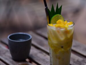 Højt glas med mango-lemonade, mangotern og kugler i bunden