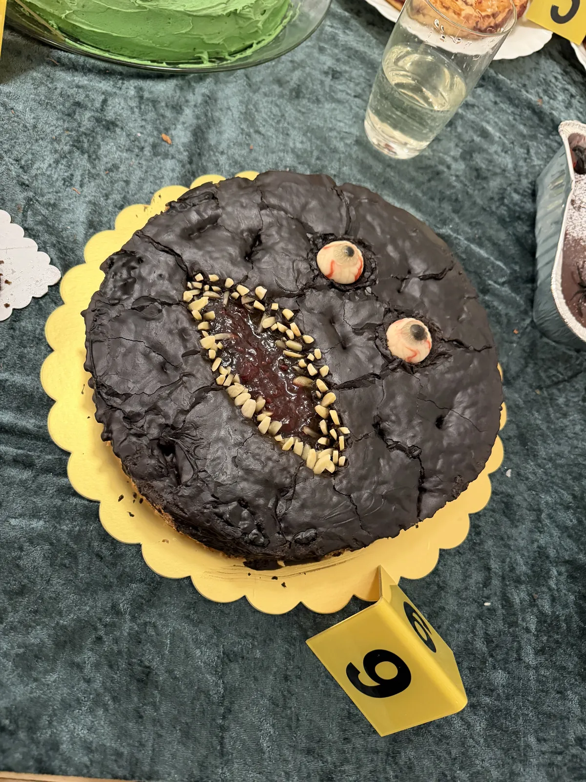 Rund monsterkage med mørk, krakeleret overflade, øjne og en mund fuld af tænder.
